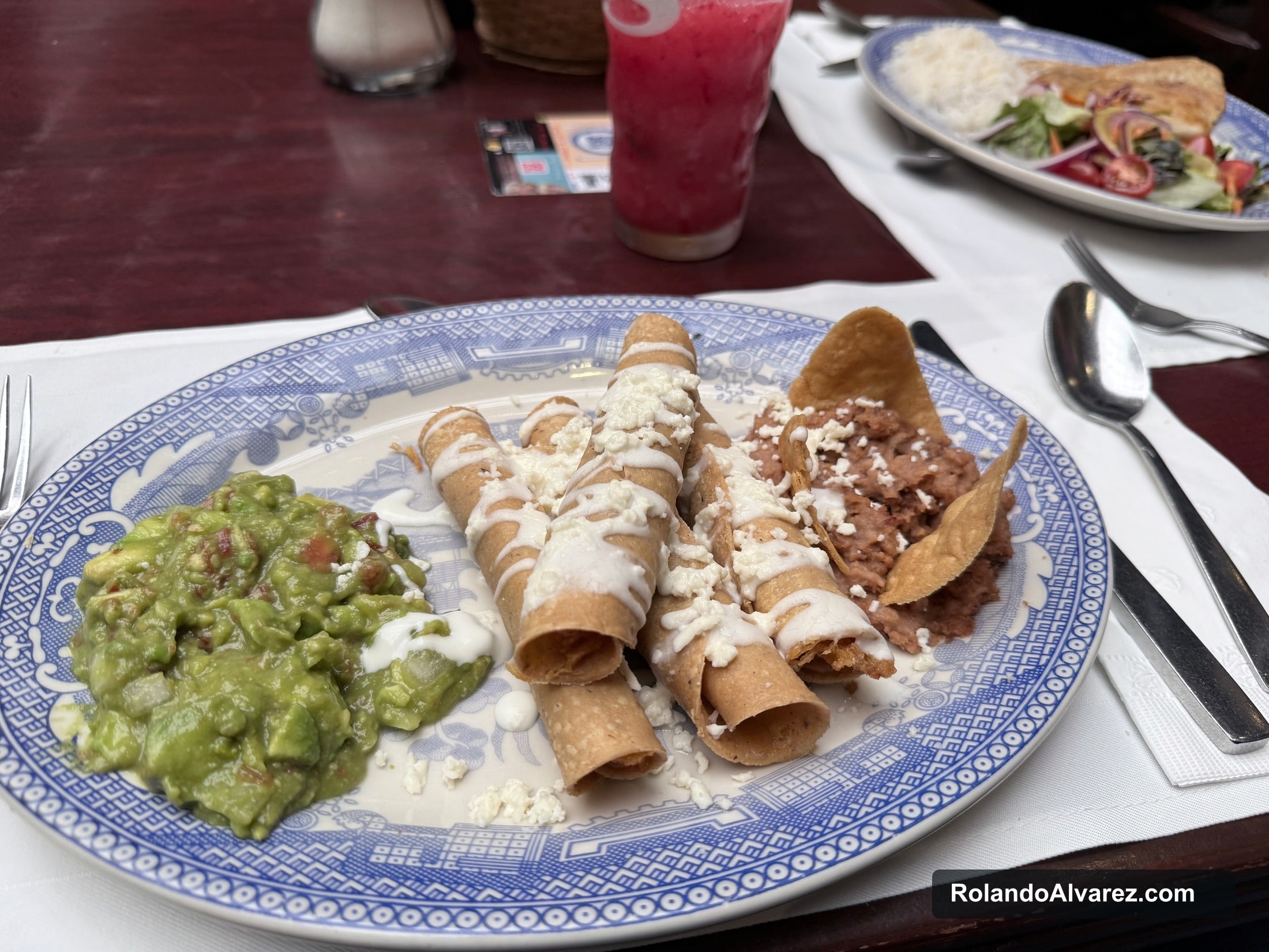 A plate of taquitos, guacamole, and beans at the House of Tiles